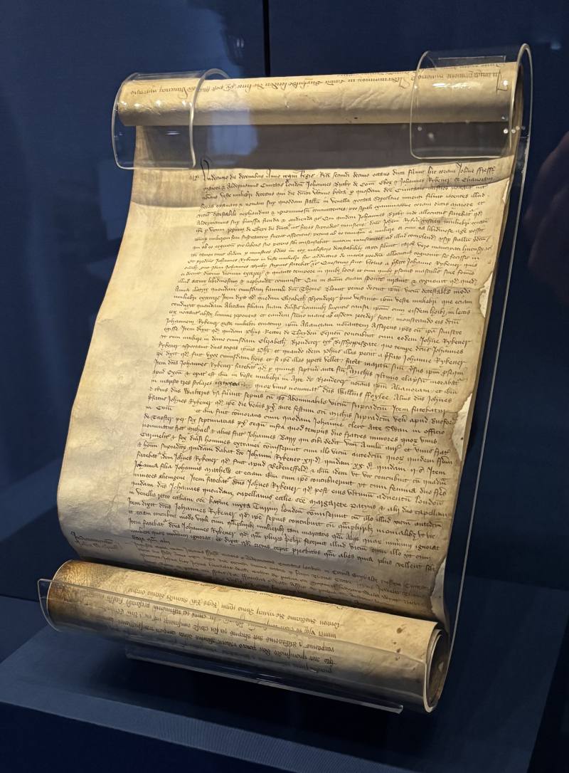 A dark blue display case in the British Library containing a scroll of the interrogation of Eleanor Rykener